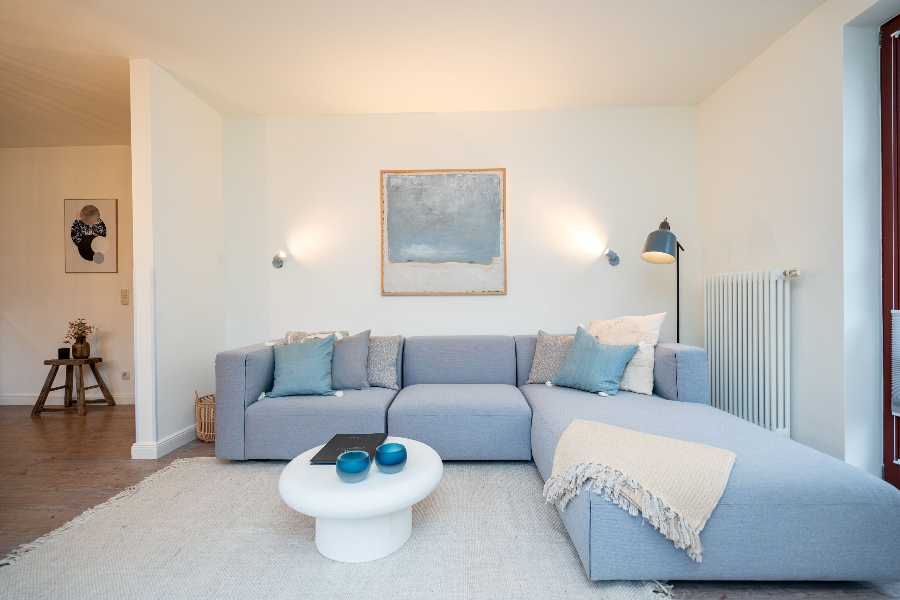 Una sala moderna con un sofá modular, una mesa de centro y un cuadro en la pared.
