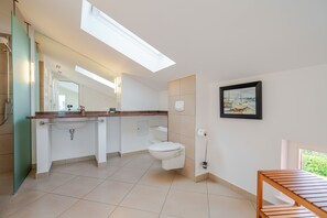 A modern bathroom with a skylight, a toilet, a sink with a towel rack, and a framed picture on the wall. - The Villa, App. 9, Germany (Heringsdorf)
