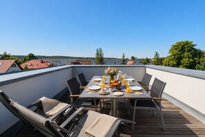 A rooftop terrace with a dining table set for four, surrounded by chairs, with a view of buildings and trees in the background. - The Villa, App. 9, Germany (Heringsdorf)