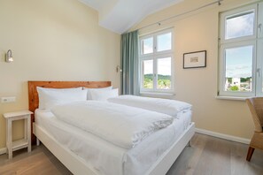 A double bed with white bedding, a nightstand, a window with curtains, and a framed picture on the wall. - The Villa, App. 9, Germany (Heringsdorf)