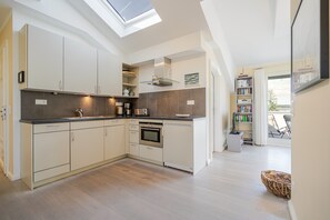 A modern kitchen with a skylight, built-in oven, and a dining area with a view. - The Villa, App. 9, Germany (Heringsdorf)