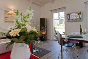 Un salon moderne avec une table à manger en verre, une cheminée et un vase de fleurs.