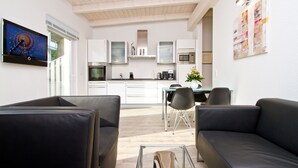 Una sala de estar moderna con un sofá de cuero negro, una mesa de centro de vidrio y un televisor de pantalla plana montado en la pared.