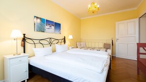 A bedroom with a large bed, two bedside tables, a chandelier, and a door. - The Villa, App. 8, Germany (Heringsdorf)