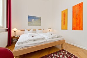 A hotel room with a bed, a nightstand, a lamp, and a painting on the wall.