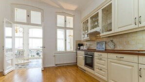 Eine geräumige Küche mit weißen Schränken, einer Holz Arbeitsplatte und Blick durch große Fenster.