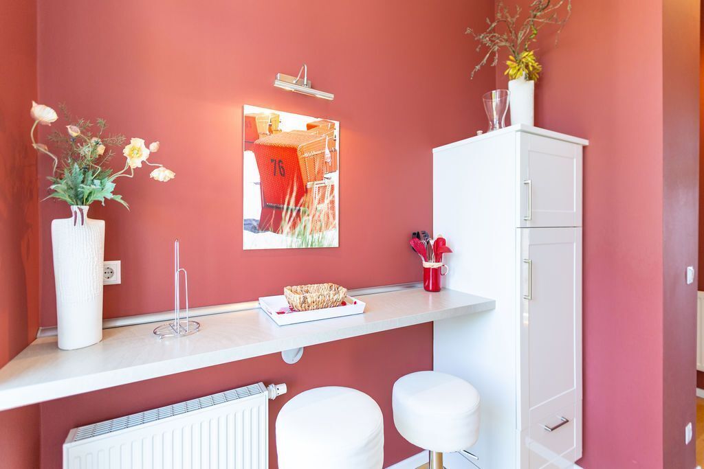 A bathroom with a white vanity, a mirror, a white radiator, and two white stools.