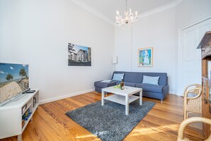 Una sala de estar con sofá, mesa de centro y televisor sobre un mueble.