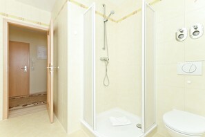 Une salle de bain avec une douche à parois de verre, des toilettes et un lavabo.