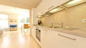 A modern kitchen with white cabinets, a stainless steel sink, and a built-in oven. - Stadtvilla Blumenhof, App. 6 (Heringsdorf)