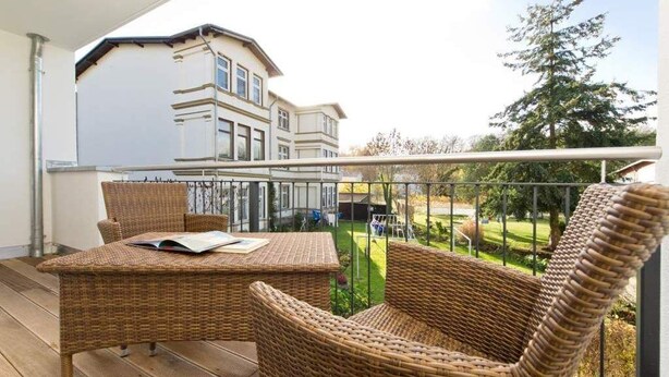 A balcony with wicker furniture, a view of a house, and a tree. - Stadtvilla Blumenhof, App. 6 (Heringsdorf)