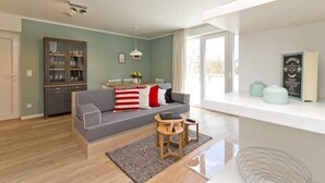 A living room with a grey sofa, a cabinet, a small table, and a window.