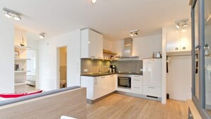 A modern kitchen with white cabinets, a patterned backsplash, and a wooden floor.