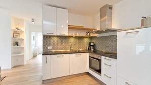 A modern kitchen with white cabinetry, patterned backsplash, and built-in appliances.