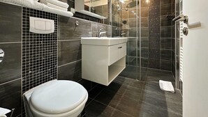 Et moderne badeværelse med toilet, vask og bruseområde.