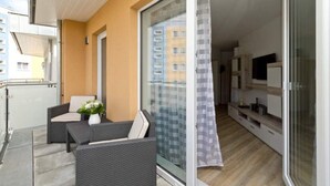 En balkon med fletningsmøbler, en skydedør og udsigt til en bygning.