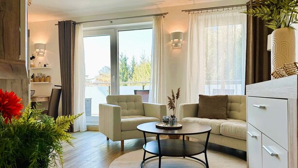 En stue med sofa, lænestole, sofabord og et spiseområde med en stol og et bord.