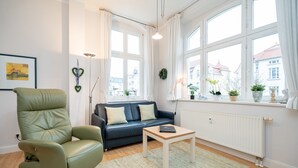 A modern living room with a green leather armchair, a dark blue sofa, and a wooden coffee table. - Villa Belvedere, App. 03 (Heringsdorf)