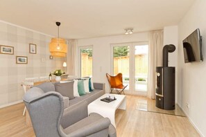 Un salon moderne avec un canapé, une table basse, un téléviseur et une cheminée.