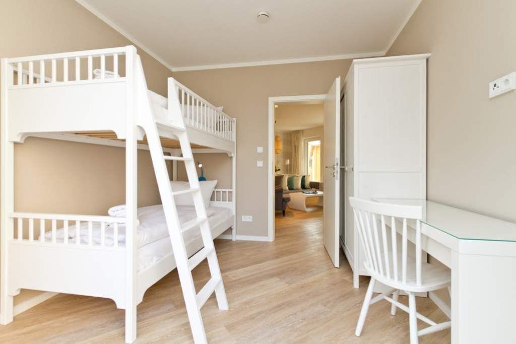 Quarto com beliches, uma escrivaninha com cadeira e um guarda-roupa.