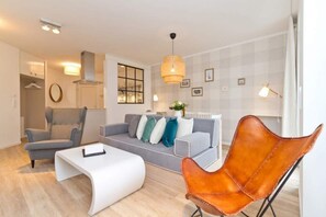 Un salon moderne avec un canapé gris, une table basse blanche, un fauteuil en cuir et un luminaire suspendu.