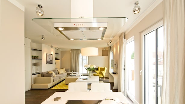A modern living room with a central island, a sofa, a yellow armchair, and a dining table with a magazine.