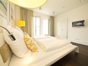 Ein modernes Hotelzimmer mit einem großen Bett, einer Nachttischlampe und einem an der Wand befestigten Fernseher.