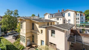 Un edificio residenziale a più piani con un balcone, un piccolo giardino e vista sulla strada.