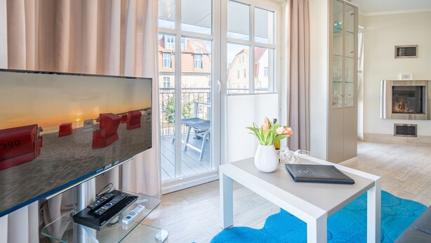 Un soggiorno moderno con una grande televisione, un tavolino in vetro e vista all'esterno.
