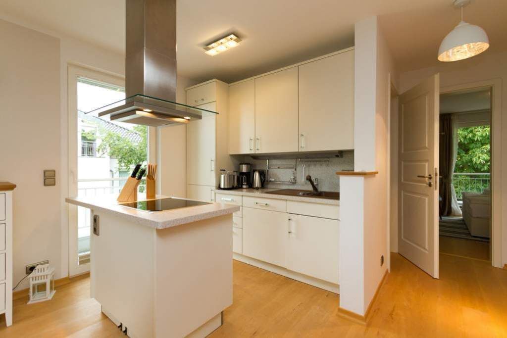 Een moderne keuken met witte kasten, een centraal eiland en een inbouwfornuis.