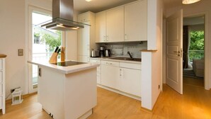 A modern kitchen with white cabinets, a central island, and a built-in stove. - Villa Barbara, App. 09 (Heringsdorf)