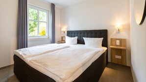 A neatly made bed with white linens in a hotel room. - Ostseedomizil Bansin, App. 1.1 (Heringsdorf)