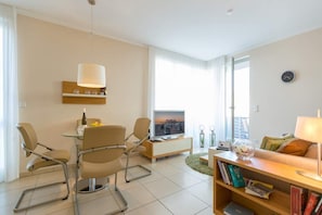 A modern living room with a dining area, a sofa, a coffee table, and a TV.