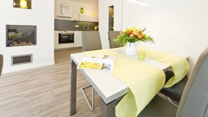 Una cocina moderna con armarios blancos, horno empotrado y comedor con mesa y sillas.