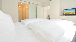 Una habitación de hotel con cama, televisor y puerta que da a un baño.