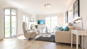 Una sala moderna con un sofá, sillones, una mesita de centro y un televisor.