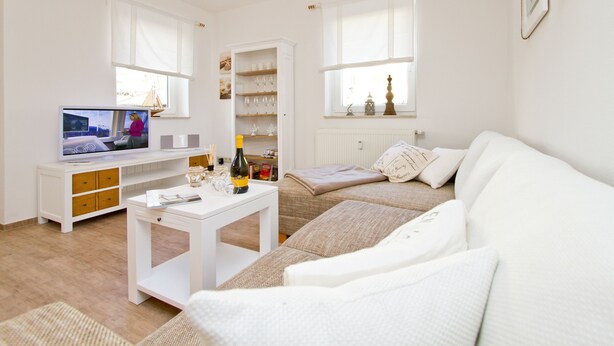 A modern living room with a white sofa, a television, a white coffee table, and a bookshelf. - Apartment house Neuer Weg, App. 02 (Heringsdorf)