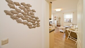 A living room with a wall-mounted fish decoration, a dining area with a table and chairs, and a kitchen in the background. - Apartment house Neuer Weg, App. 02 (Heringsdorf)