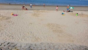A beach with people and boats in the background. - Villa in Zeeland near Clean Beaches (Colijnsplaat)