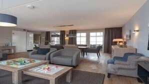 A modern living room with a sofa, armchairs, a coffee table, and a dining area. - Villa in Zeeland near Clean Beaches (Colijnsplaat)