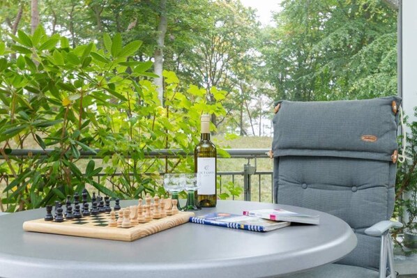 Una mesa redonda con un tablero de ajedrez, una botella de vino y una revista.
