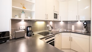 A modern kitchen with white cabinets, a built-in microwave, a coffee maker, and a toaster. - Villa Marfa, App. 02 (Heringsdorf)