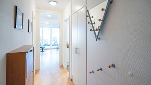 A hallway with a wooden counter, a coat rack, and a door leading to a bright room with large windows. - Villa Marfa, App. 02 (Heringsdorf)
