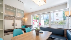 A modern kitchen with a dining area, a built-in bench, and a view of the outside. - Villa Limora, App. 02 (Heringsdorf)