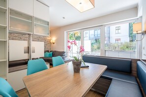 Une cuisine moderne avec un coin repas, un banc intégré et une vue sur l’extérieur.