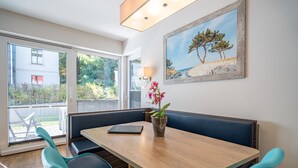 A dining area with a wooden table, teal chairs, and a bench. There is a potted plant on the table and a painting on the wall. - Villa Limora, App. 02 (Heringsdorf)