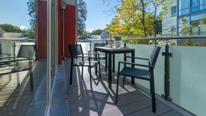 A balcony with chairs and a table, overlooking a building and trees. - Villa Limora, apt. 04 (Heringsdorf)