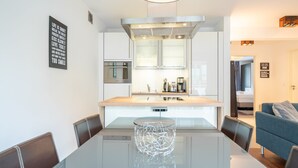 A modern kitchen with a central island, a dining table, and a sofa in a living area. - Villa Limora, apt. 04 (Heringsdorf)