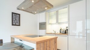 A modern kitchen with white cabinets, a wooden island, and a stainless steel oven. - Villa Limora, apt. 04 (Heringsdorf)