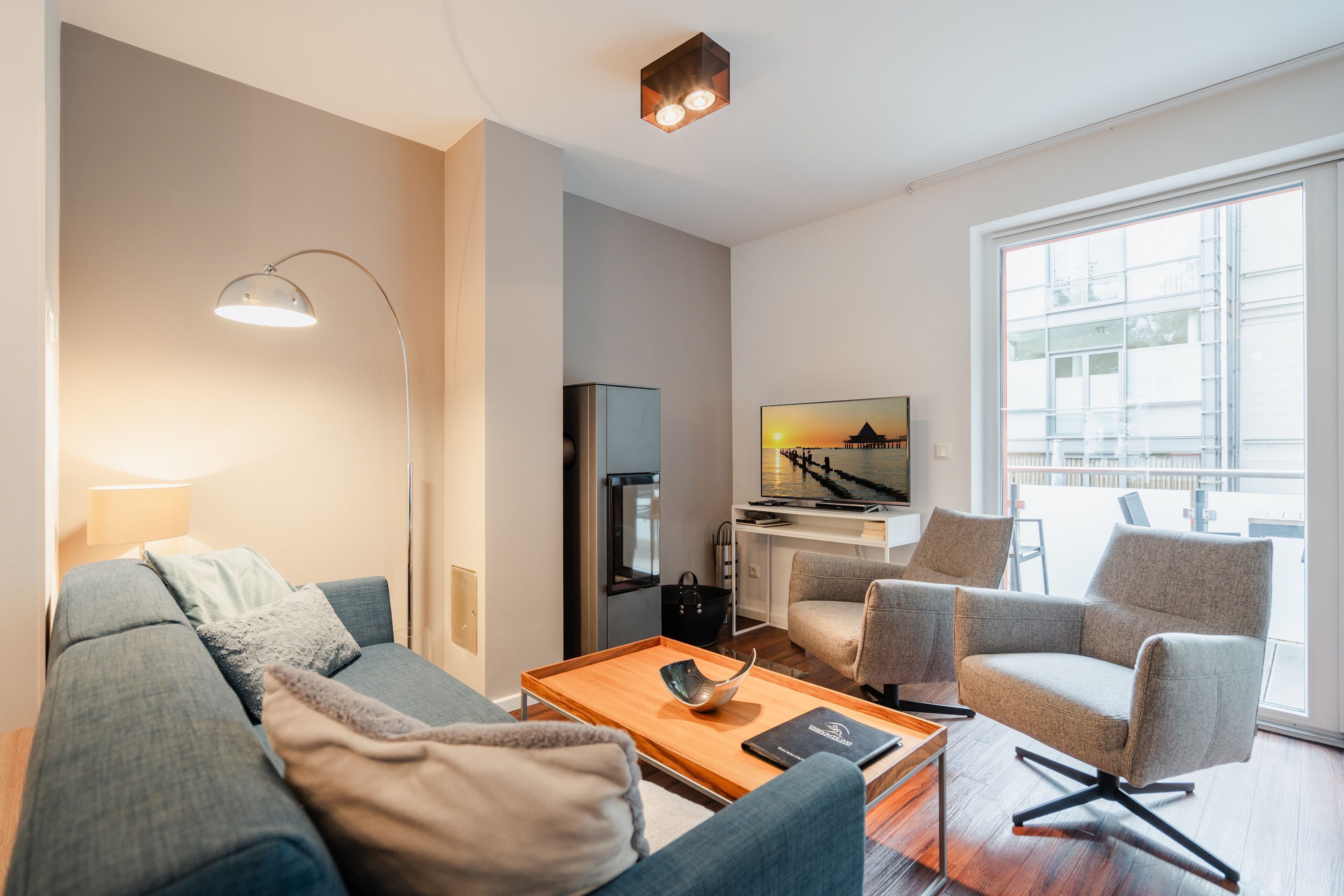 A modern living room with a sofa, armchairs, a coffee table, and a TV.